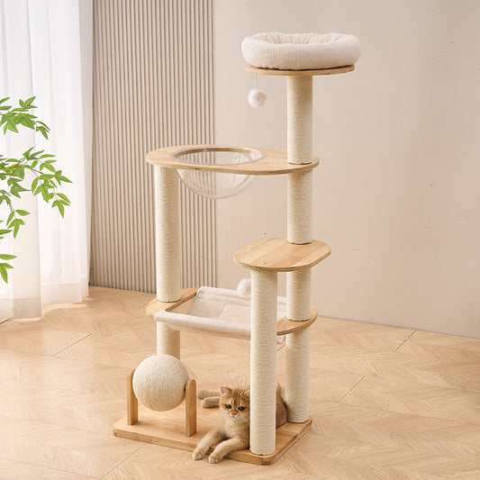 A solid wood cat tree with multiple levels and a cat sitting on the bottom level in a room with a plant and curtains.