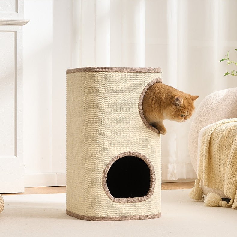 A ginger cat sits inside the circular opening of a tall, cylindrical and large cat tree made of cream-colored woven rope material with brown trim, set in a bright, modern room.