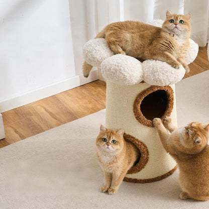 A three-level cat condo with a plush cream top, a beige wrapped body, and brown trim, shown in a home setting with three orange tabby cats interacting with it.